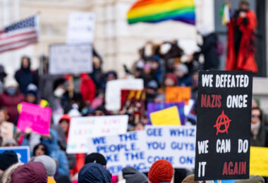 Protester at the Minnesota State Capitol on February 5, 2025 holding up a sign that reads "We defeated nazis once we can do it again".