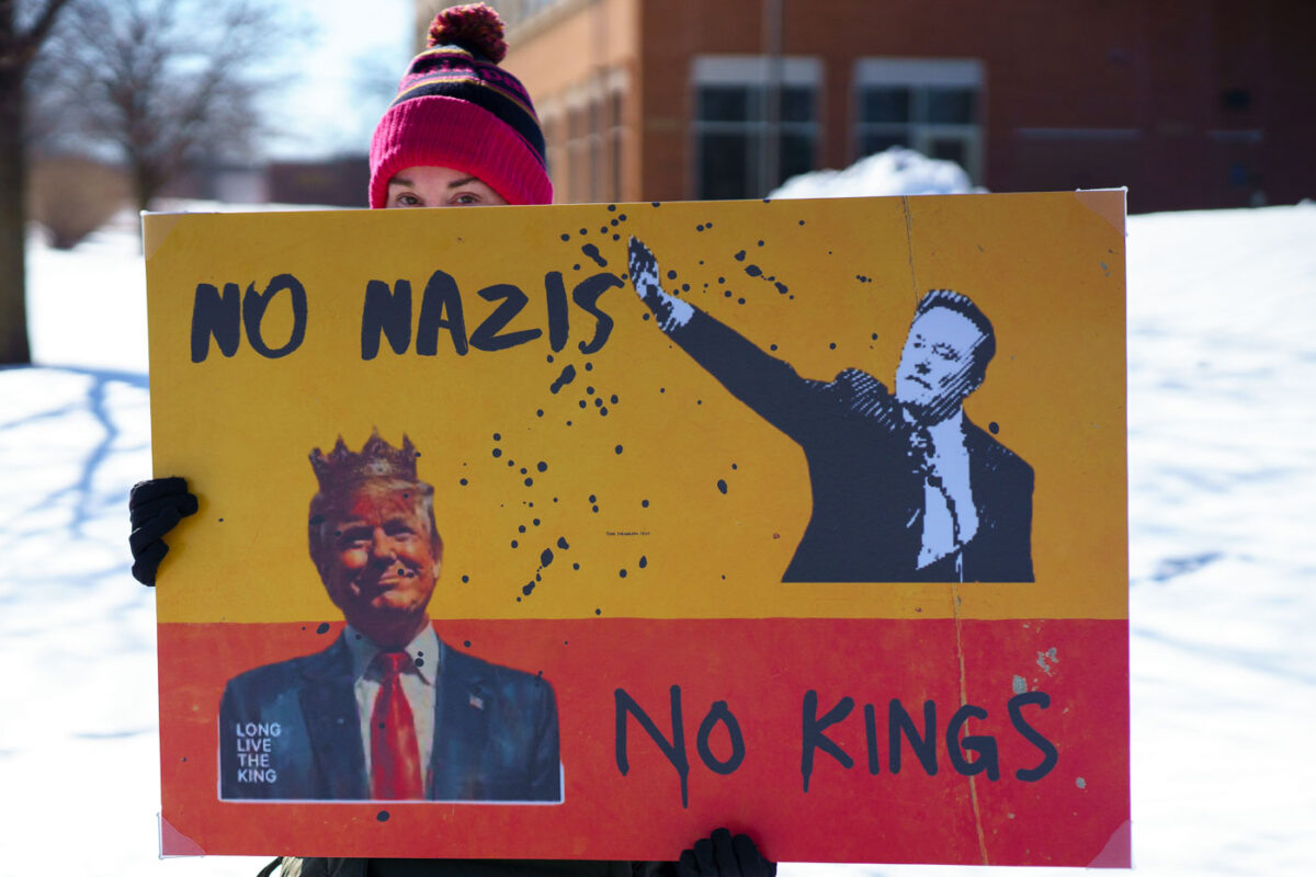 Protester holds a sign up that reads "No Nazis No Kings" at a "Tesla Takeover" protest in front of a Tesla facility in Minneapolis on February 22, 2025.