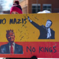 Protester holds a sign up that reads "No Nazis No Kings" at a "Tesla Takedown" protest in front of a Tesla facility in Minneapolis on February 22, 2025.