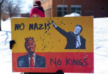 Protester holds a sign up that reads "No Nazis No Kings" at a "Tesla Takedown" protest in front of a Tesla facility in Minneapolis on February 22, 2025.