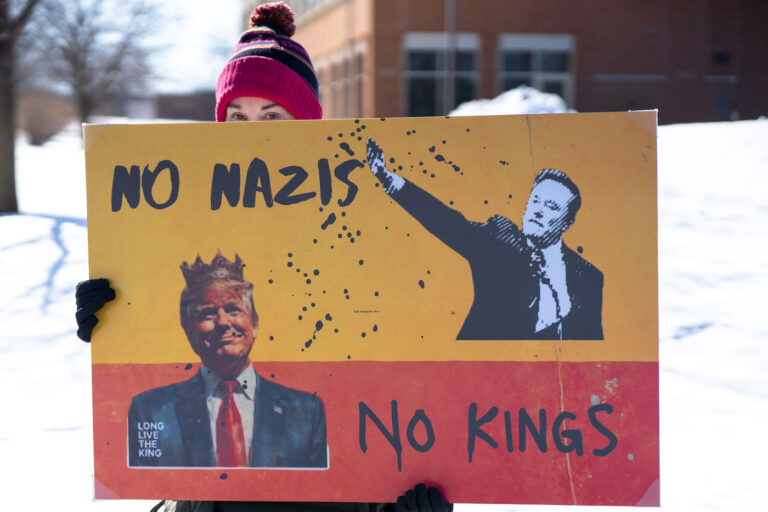 Tesla Takedown Protest Minneapolis No Nazis No Kings 2 Protester holds a sign up that reads "No Nazis No Kings" at a "Tesla Takedown" protest in front of a Tesla facility in Minneapolis on February 22, 2025.