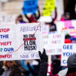 Protester at the Minnesota State Capitol on February 5, 2025 holding up a sign that reads "Stop the theft of our info!" "Absolutely no one voted for elon musk! None of us!".