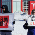 Protesters hold up signs that read "Felon MuSSK" "Nobody Elected Elon!" at a "Tesla Takeover" protest in front of a Tesla facility in Minneapolis on February 22, 2025.