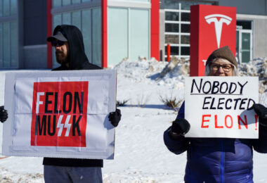 Protesters hold up signs that read "Felon MuSSK" "Nobody Elected Elon!" at a "Tesla Takedown" protest in front of a Tesla facility in Minneapolis on February 22, 2025.