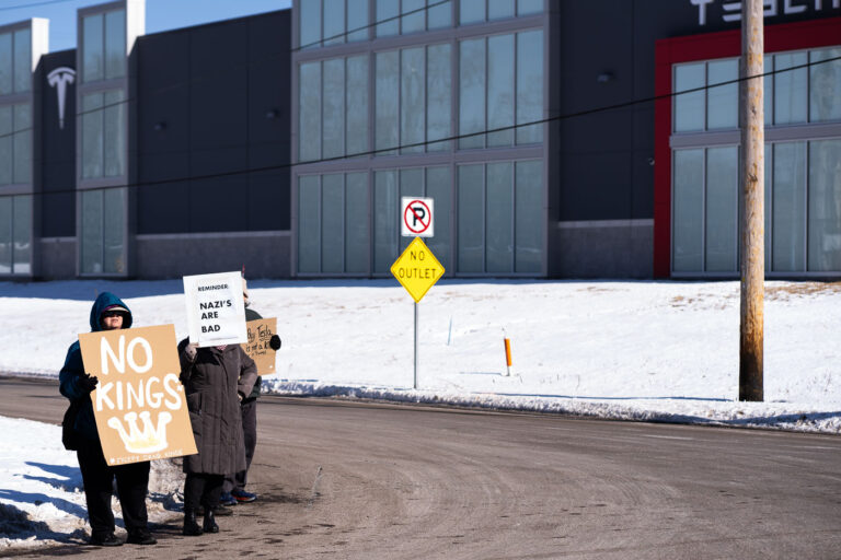 Tesla Minneapolis Protest February 22 2025 2 Protesters hold up signs reading "No Kings (Except Drag Kings) "Reminder: Nazi's Are Bad" at a "Tesla Takedown" protest in front of a Tesla facility in Minneapolis on February 22, 2025.