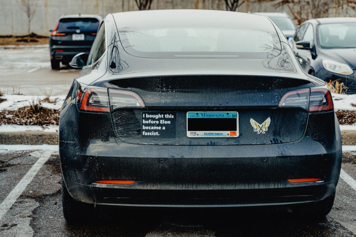 A Tesla vehicle seen in Minneapolis with Tesla branding removed and a sticker reading "I bought this before Elon became a fascist.".