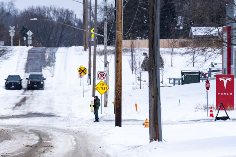 Tesla protester and Golden Valley police 2 Protester outside a Telsa showroom in Minneapolis (Golden Valley) with staged Golden Valley police squad cars.