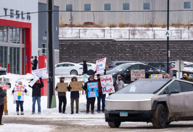 Protesters at the Tesla service center just outside of Minneapolis. Signs reading “Unplug Mad King Musk”, “This car runs on fascism”, “Who buys cars from a nazi?”, “Say no to doge”, “Don’t buy swasticars, BAD DOGE!”. Protest is part of a nationwide "TeslaTakedown" protest that seems to have originated on Bluesky.