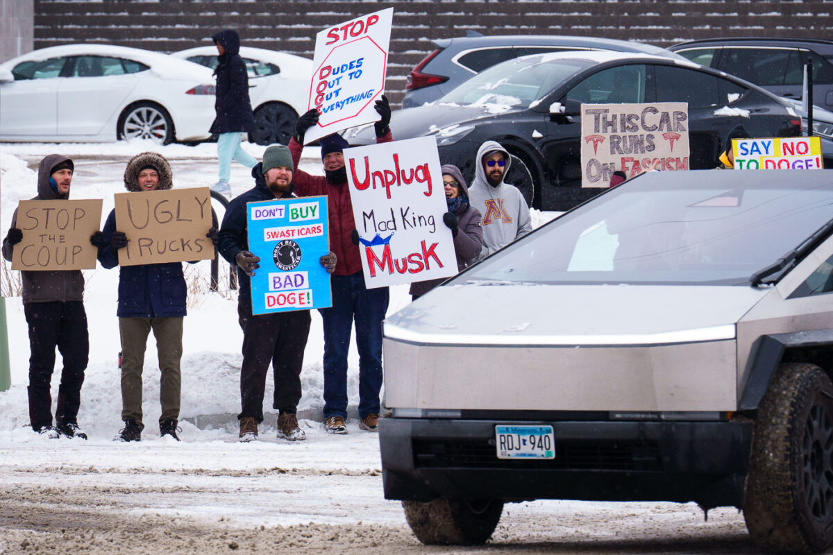 Protesters at a Tesla Service Center in Golden Valley, MN (Minneapolis) on January 15, 2025. Signs being held up that read "This car runs on fascism"