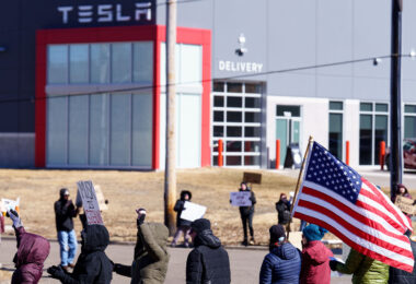 Protester with an American flag outside a Tesla facility just outside of Minneapolis.