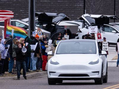 White Tesla Passes "Musk Must Go" Signs in Golden Valley