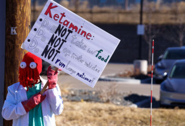 Protester in Minneapolis (Golden Valley) holds up a protest sign at a Tesla facility.