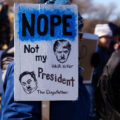 Protester holding up a sign that reads 

"Nope Not my President"

"Hair Hitler"
"The Dogefather"

Protesters have gathered each Saturday for weeks now at this Tesla Facility just outside of Minneapolis (Golden Valley).