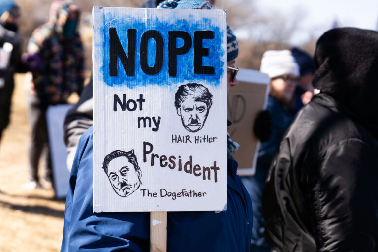 NOPE Not My President 1 Protester holding up a sign that reads "Nope Not my President""Hair Hitler""The Dogefather"Protesters have gathered each Saturday for weeks now at this Tesla Facility just outside of Minneapolis (Golden Valley).