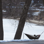 A couple in a hammock on the lake on the first 60 degree day of the year in Minneapolis.