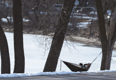 A couple in a hammock on the lake on the first 60 degree day of the year in Minneapolis.