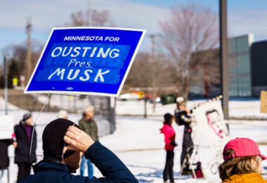 Protester with a sign reading "Minnesota for Ousting Pres. Musk" at a Tesla Facility just outside of Minneapolis (Golden Valley) on March 8, 2025.

This is the 4th week in a row protesters have gathered here as part of the nationwide Tesla Takedown organizing.