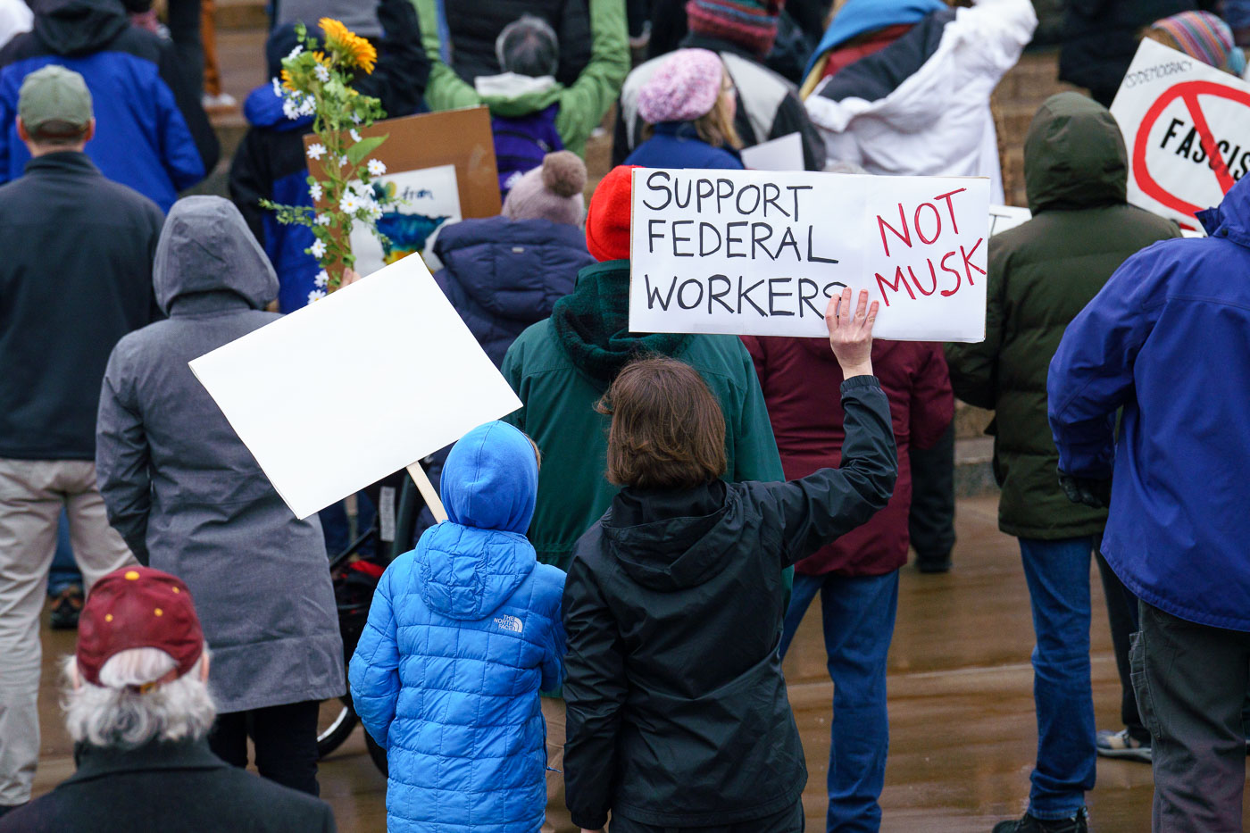 Protest holding sign reading Support Federal Workers Not Musk