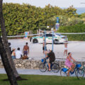 Squad car drives down past a volleyball game in south beach