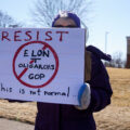 Protester holding up a sign that reads "Resist Elon Tesla Oligarchs GOP This is not normal" outside a Tesla facility in just outside of Minneapolis (Golden Valley) on March 1st, 2025. 

This is the third weekend in a row they've gathered to protest the actions of Elon Musk and the current administration