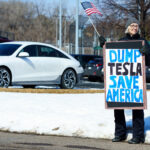 Tesla Takedown Dump Tesla Save America 3 Protester holds a sign that reads "Dump Tesla Save America". Seen at a Tesla facility just outside of Minneapolis (Golden Valley) on March 8, 2025.This is the 4th week in a row protesters have gathered here as part of the nationwide Tesla Takedown organizing.