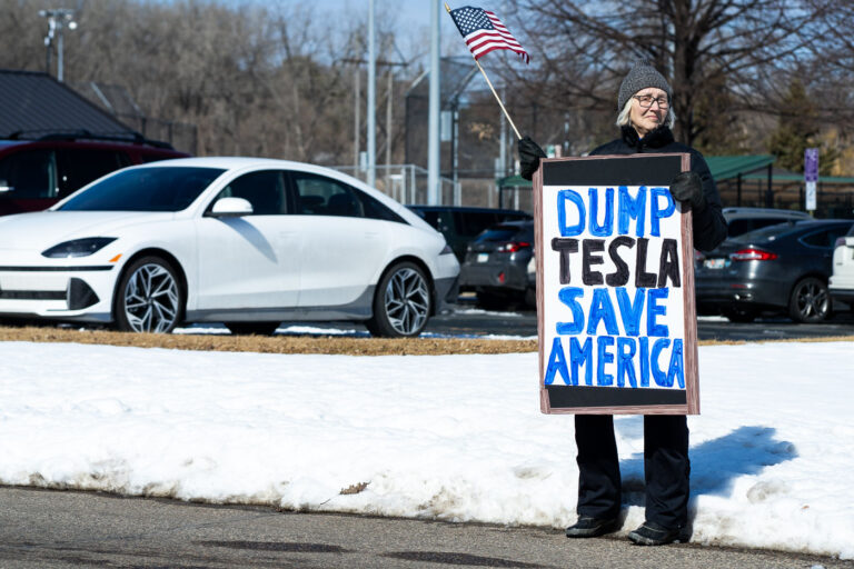 Tesla Takedown Dump Tesla Save America 3 Protester holds a sign that reads "Dump Tesla Save America". Seen at a Tesla facility just outside of Minneapolis (Golden Valley) on March 8, 2025.This is the 4th week in a row protesters have gathered here as part of the nationwide Tesla Takedown organizing.