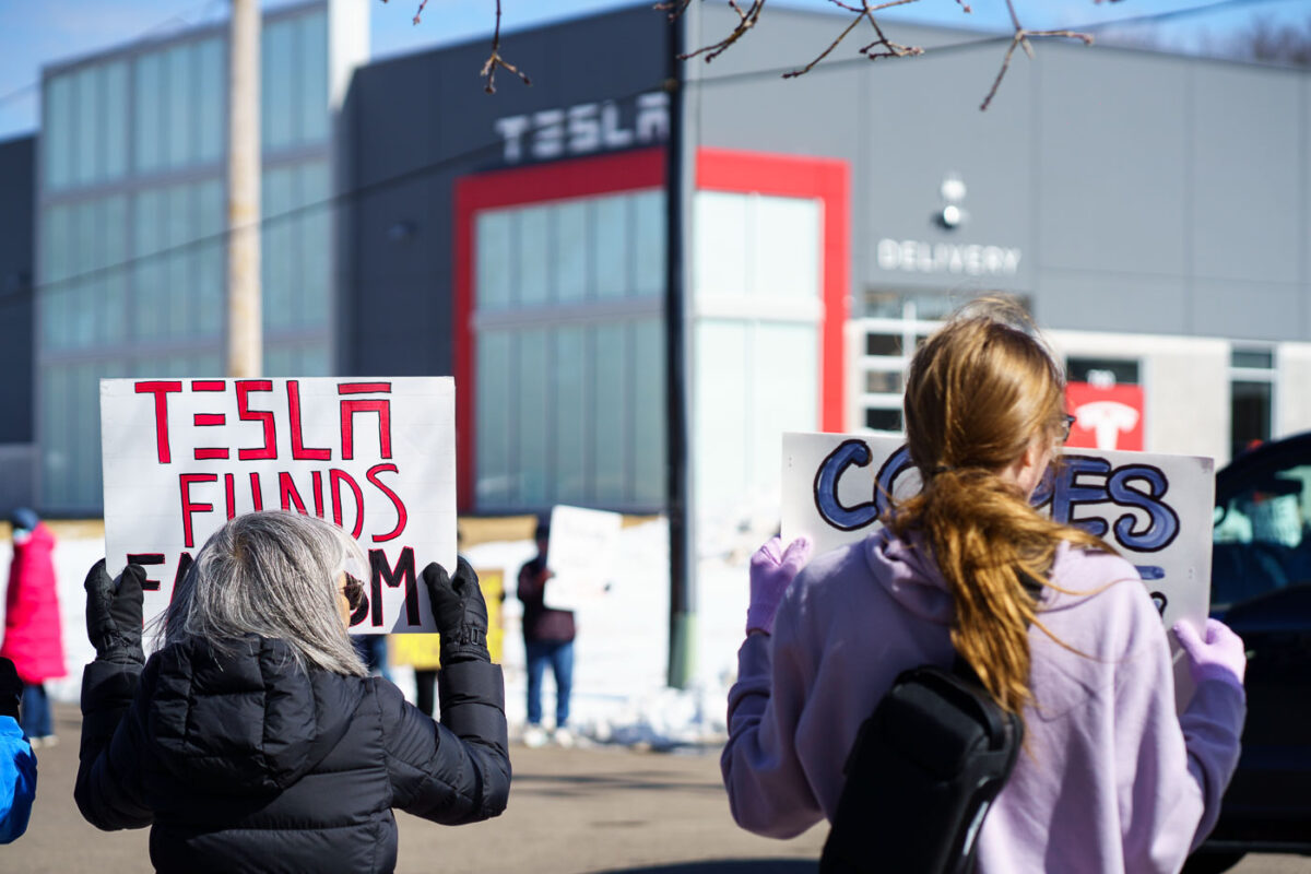 Protesters hold signs outside a Tesla showroom in Golden Valley(Minneapolis) on March 8,2025.