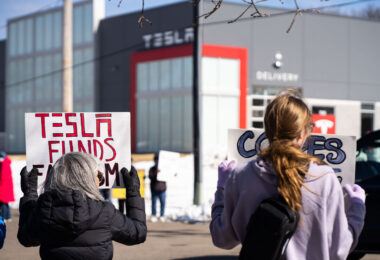 Protesters hold signs outside a Tesla showroom in Golden Valley(Minneapolis) on March 8,2025.