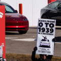 Protesters hold up signs reading "Deport Musk" and "Tesla The Swasticar" at a protest outside a Tesla facility in Minneapolis(Golden Valley) on March 1, 2025. The protests are part of nationwide "Tesla Takedown" protests targeting Musk, Tesla and the Trump Administration.
