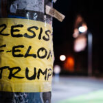 Taped to a pole at Harvard University, "Resist F-Elon Trump at Harvard University".
