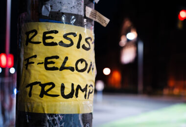 Taped to a pole at Harvard University, "Resist F-Elon Trump at Harvard University".