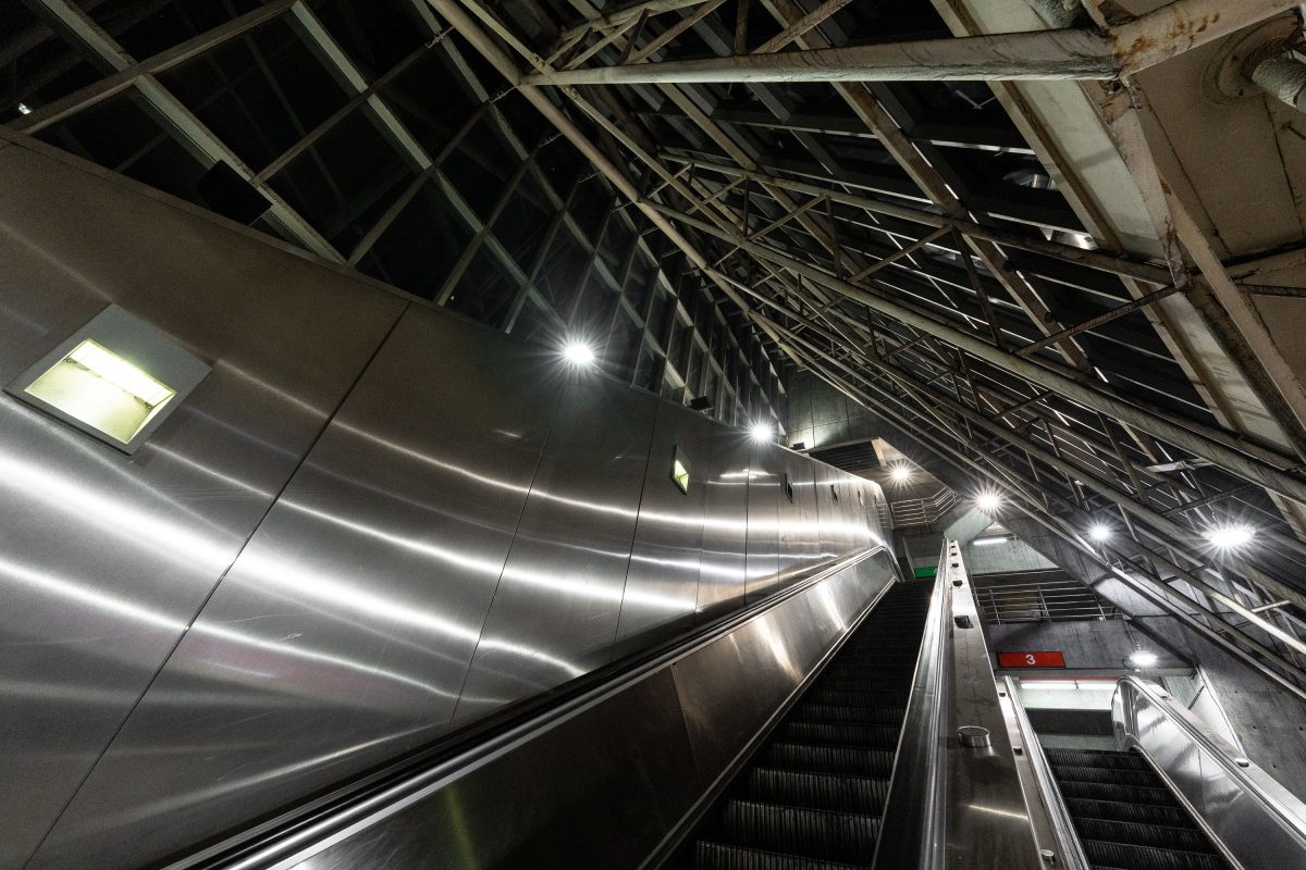 Escalators at MBTA Alewife Station in Cambridge with metal ceiling panels and industrial lighting.