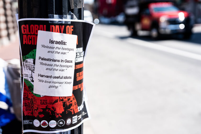 Global day of action protest flyers at Harvard University 2 A layered set of flyers taped to a pole near Harvard Square reveals the intense atmosphere surrounding debates on the Israel–Gaza conflict. The underlying poster promotes a “Global Day of Action for Gaza,” while a separate sheet on top adds a sharply critical response, contrasting the slogans of various groups with mocking commentary. This kind of street pole collage — layered, confrontational, and public — captures the friction between activism and counter-activism common around Harvard Square’s sidewalks, where local and global politics often meet in view of passing students and commuters.