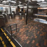 State Street Station Fare Control, Boston 3 The entrance and fare control area at State Street Station, a key interchange in downtown Boston where the Orange Line and Blue Line intersect. The station opened in 1908 as part of the Washington Street Tunnel and remains one of the MBTA’s oldest continuously operating rapid transit facilities. Brick flooring, steel columns, and low ceilings reflect early 20th-century subway construction, while modern fare gates and electronic arrival boards show later upgrades layered onto the original structure. The signage directing riders to Oak Grove, Forest Hills, and Wonderland highlights the station’s role as a transfer point connecting North Shore riders, downtown commuters, and the broader MBTA network.
