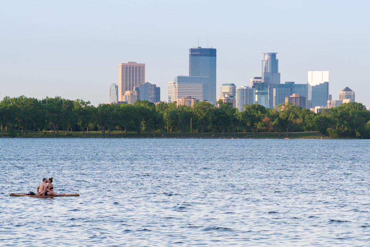 Couple kisses on a Minneapolis Lake in front of the downtown skyline