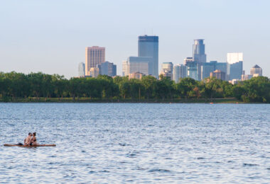 A couple on Bde Maka Ska with the Minneapolis city skyline behind