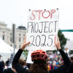 Protester with a Stop 2025! protest sign at a No Kings rally in June.Despite warnings from the law enforcement not to attend today’s No Kings rally after this mornings shootings of Minnesota lawmakers with the killer on the lose, the No Kings Rally is happening at the Minnesota State Capitol in St. Paul.