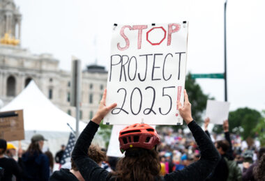 Protester with a Stop 2025! protest sign at a No Kings rally in June.

Despite warnings from the law enforcement not to attend today’s No Kings rally after this mornings shootings of Minnesota lawmakers with the killer on the lose, the No Kings Rally is happening at the Minnesota State Capitol in St. Paul.