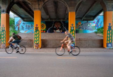 Bikers ride past a new mural on the Midtown Greenway in South Minneapolis.