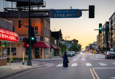A woman walks across Lake Street outside of Uptown Pizza during a mid August sunset.