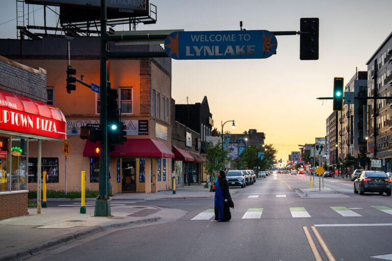 Uptown Pizza at Lake Street and Grand Ave 1 A woman walks across Lake Street outside of Uptown Pizza during a mid August sunset.