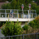 A cyclist travels across the Martin Olav Sabo Bridge, a dedicated pedestrian and bicycle suspension bridge spanning Hiawatha Avenue in Minneapolis. Opened in 2007, the bridge was designed to provide a safe, grade-separated connection for trail users along the Midtown Greenway, avoiding the busy highway and light-rail tracks below. The bridge reflects Minneapolis’ investment in protected urban cycling infrastructure, supporting its reputation as one of the most bike-friendly cities in the United States.