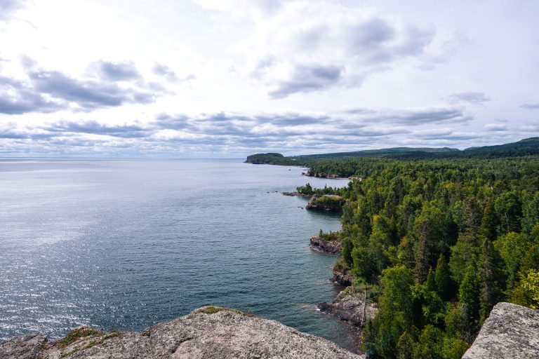 Rocky shoreline of Lake Superior along Tettegouche State Park with forested cliffs and distant headlands.