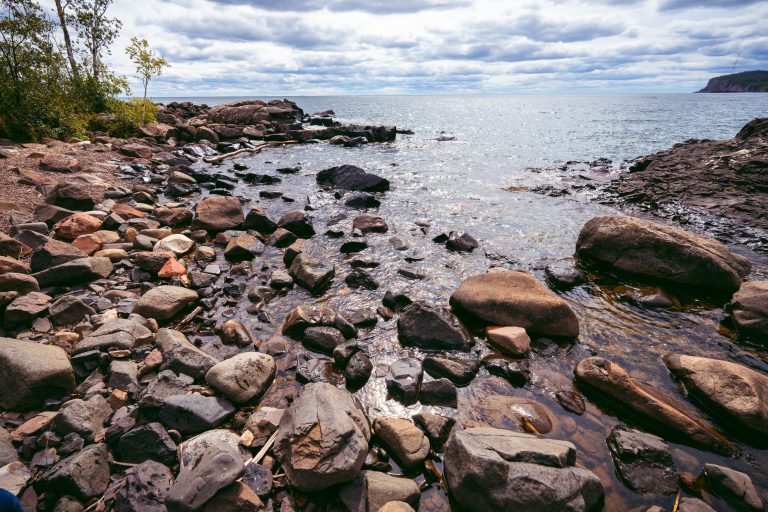 Rocky shoreline of Lake Superior at Tettegouche State Park with boulders and calm water.