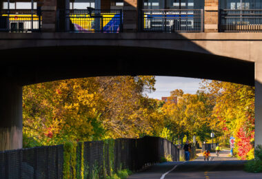 Bikers, walkers on the Midtown Greenway as a bus leaves the Uptown Transit Station above. 

Uptown Minneapolis, October 2025