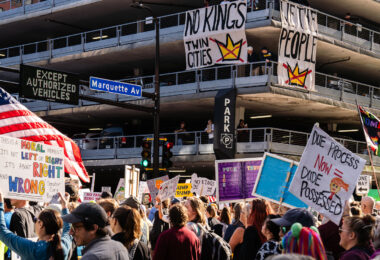 Banners hanging from a parking garage reading "NO KINGS TWIN CITIES" and "WE THE PEOPLE".

Thousands protest in Downtown Minneapolis on Saturday October 18, 2025 as part of nationwide “No Kings!” protest.