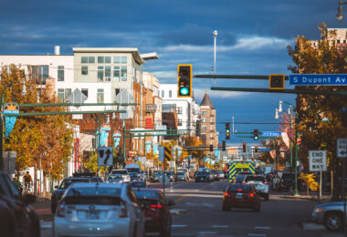 Traffic flows through the LynLake district of Minneapolis at South Dupont and Bryant Avenue, a neighborhood long known as a crossroads between Uptown and Whittier. Once a streetcar junction for the Twin City Rapid Transit Company, the area declined after the 1950s but later rebounded through waves of redevelopment and independent business growth. Today, LynLake blends historic brick storefronts with modern apartments and restaurants, reflecting Minneapolis’s broader push toward urban density and transit-oriented design along the former streetcar corridor.