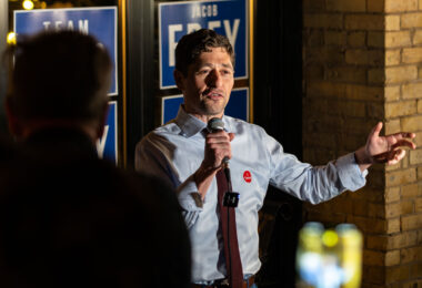 Minneapolis Mayor Jacob Frey speaks to supporters during his 2025 election night gathering, held at a downtown venue adorned with campaign posters. Frey, seeking reelection in the aftermath of years of national attention on Minneapolis politics, reflected on civic challenges and vowed continued focus on rebuilding trust and progress following the city’s social and economic transformation since 2020.