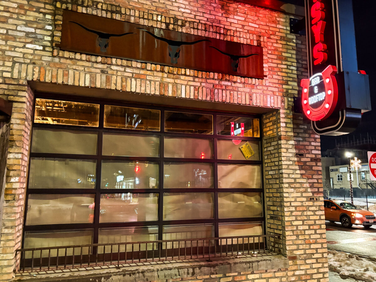 Daisys Uptown bar exterior at night, with red neon signs and snow along the curb
