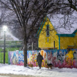 Mural on a Minneapolis fence during snowfall 4 Someone walks their dogs in South Minneapolis. Walking past a painted fence that reads "We who believe in freedom cannot rest until it comes."